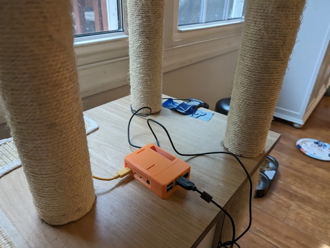 A Raspberry Pi and webcam sitting on top of a cat tree